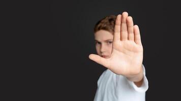 Domestic violence and child abuse. Boy showing stop gesture with his hand, gray background photo