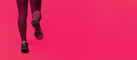 Cropped of black woman runner legs while jogging over red background, empty space photo