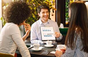 Managers analyzing chart at a business lunch, discussing successful project at cafe, free space photo