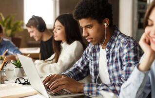 Student learning lessons in school library, making research on laptop and browse internet photo