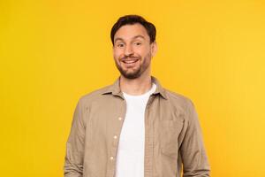 A man is standing upright in front of a bright yellow background. He appears to be looking straight ahead, with his hands by his sides, smiling at camera photo
