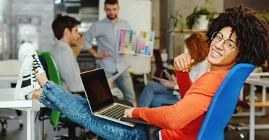 Smiling man enjoying work in modern comfortable cozy co-working space, relaxing while his friend discussing project, panorama photo