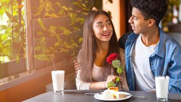 africano americano chico y niña son sentado a un mesa, con un soltero rojo Rosa metido en el centro. ellos Aparecer a ser comprometido en conversación, con el chico gesticulando hacia el Rosa. foto