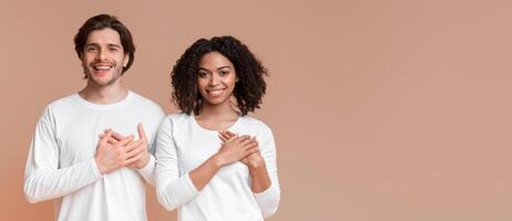 Grateful Multiracial Couple Expressing Gratitude With Hands On Chest, Posing Together Over Yellow Background With Free Space photo