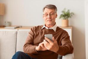 Phone User. Happy Senior Man Using Smartphone Browsing Internet Sitting On Couch At Home. Selective Focus photo