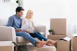 Husband And Wife Using Laptop Looking Design Project Sitting On Couch In Own House. Moving Into New Home. Copy Space photo
