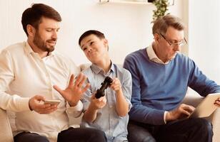Indifference. Busy Father And Grandfather Refusing To Play Game With Boy Siitting On Sofa Indoor. Selective Focus photo