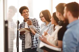Students writing tasks on whiteboard in class, laughing with classmates photo