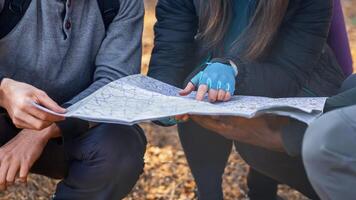 Map and navigation concept. Three unrecognizable multiethnic friends holding map, got lost at countryside, cropped photo