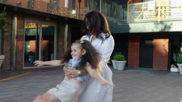 Mother plays with daughter in urban setting near cafe in late afternoon video