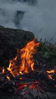 Close-Up of Campfire Burning on Mountain Cliffside with Rolling Fog and Dramatic Evening Ambiance in Wilderness Setting video