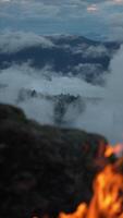 Campfire on Foggy Mountain Overlook with Dramatic Clouds and Distant Peaks in Serene and Mystical Evening Light video