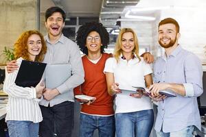 A diverse group of individuals standing closely next to each other in a row, looking towards the camera. They appear to be engaged in a conversation or event, showing unity and togetherness. photo