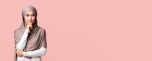 Making plans. Portrait of pensive arabic woman in hijab thinking about something, touching chin and looking aside at copy space over pink background photo