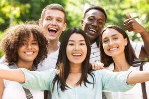 Selfie Fun. Group of multi-ethnic teen friends taking self portrait picture outdoors and sincerely smiling at camera photo