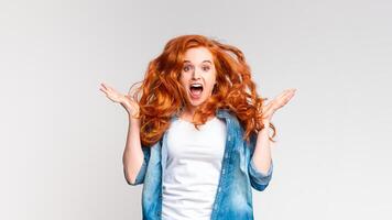 A woman with vibrant red hair is shown making a surprised facial expression gesturing, with her eyes widened and mouth slightly open. Her expression conveys shock or disbelief. photo