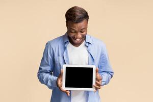 Mobile App. Afro Man Holding Digital Tablet With Blank Screen Standing Over Yellow Studio Background. Mockup photo