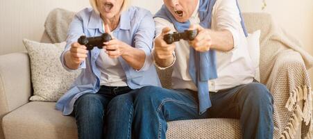 Modern grandparents. Senior spouses enjoying playing videogames on playstation, resting at home photo