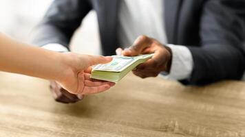A person is receiving a stack of cash from another person. photo