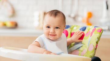 An infant is sitting in a high chair in a homey kitchen. The atmosphere is cheerful and relaxed, highlighting the simple joys of mealtime in a family kitchen. photo