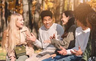 Group of happy international teenagers talking and laughing in park, close up photo