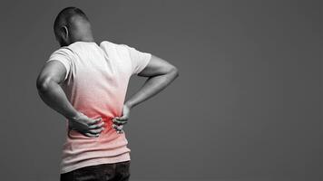 Afro guy holding both hands on lower back, pain in spine, inflamed zone highlighted in red, white background, free space photo