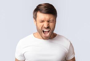Anger Expression. Portrait Of Crazy Man Shouting Furiously Over White Studio Background. Copy Space photo
