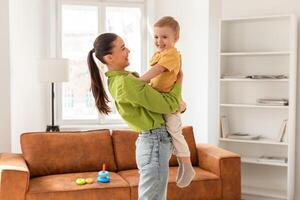 A woman is seen holding a small child in her arms. Mother face is not visible, but her arms are securely wrapped around her son. Kid appears to be resting peacefully in her embrace. photo
