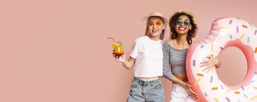 This image shows two happy friends posing with a donut pool float on a pink background. Both are smiling and wearing sunglasses. This image is perfect for representing summertime fun and friendship. photo