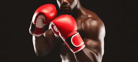 A close-up shot of a boxer wearing red boxing gloves against a black background. The boxer is looking directly at the camera with a determined expression. photo