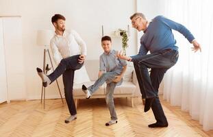 Happy Grandfather With Mature Son And Grandson Having Fun Pretending To Play A Guitar At Home. Multi-Generational Male Friendship photo