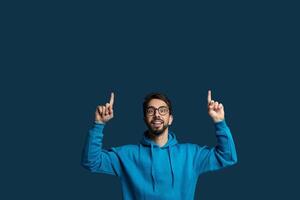A man wearing a blue hoodie is standing with his hands raised in the air. He appears to be in a position of surrender or submission, copy space photo