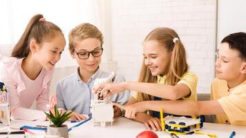 This image shows four children working together on a STEM project in a classroom setting. The children appear to be focused and engaged in their work, and they are all smiling photo