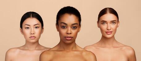 Three Mixed Models Girls Posing Wrapped In Bath Towels Looking At Camera Standing Over Gray Background. Studio Shot photo