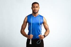 Studio Shot Of Young Black Muscular Man With Jumping Rope Around His Neck Over Yellow Background, Copyspace photo