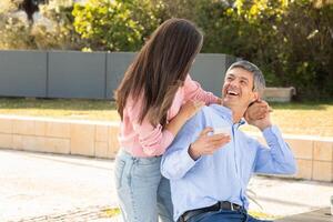 A man and woman are sharing a light-hearted conversation while sitting outside in a park. The atmosphere is cheerful, and the sun is shining brightly. photo
