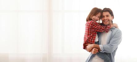 Smiling daddy and daughter posing at home over big window, copy space photo