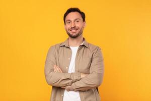 A man is standing confidently with his arms crossed in front of a bright yellow background, displaying a posture of strength and determination photo