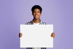 Happy guy showing blank placard with copy space for your text, pink background photo