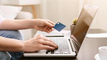 Lady holding a credit card in one hand while operating a laptop with the other hand, focused on making an online transaction, with computer for shopping or banking. photo