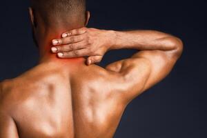 Back View. Shirtless black man suffering from pain in neck, symptom of cervical chondrosis, red spot, trauma photo
