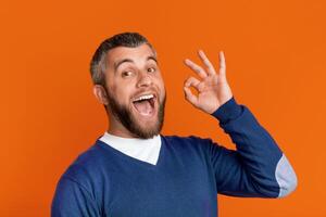 A man is playfully contorting his face with his hands, shaping it into a goofy and humorous expression. He seems to be engaging in a lighthearted and comical moment. photo