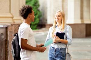 Classmates talking in college campus, having break between classes, resting outdoors photo