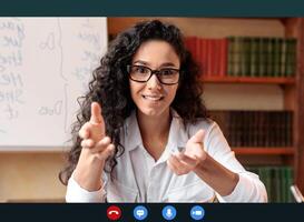 Virtual Tutoring. Female Professor Wearing Eyeglasses Having Call, Teaching Foreign Languages, Talking To Camera During Online Lesson, Board With English Grammar Rules In The Background photo