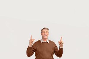 Excited Senior Man Pointing Fingers Up Standing Over White Studio Background. Free Space For Text photo