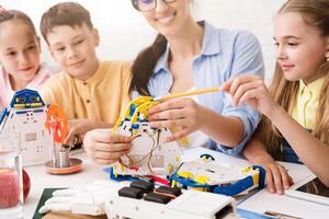 A teacher guides a group of children as they work together to build a robot. The students are focused and engaged, learning about STEM concepts through hands-on experience. photo