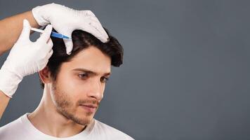 Man with hair loss problem receiving injection in head, grey background, empty space photo