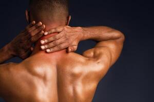 Sports Injury. Back view of naked black man suffering from pain in neck, symptom of cervical chondrosis, red spot photo