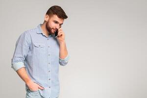 Handsome man talking on cellphone and looking away on studio background, panorama, copy space photo