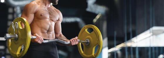 Weightlifting. Muscular bodybuilder exercising with heavy barbell in gym, panorama with copy space, cropped photo